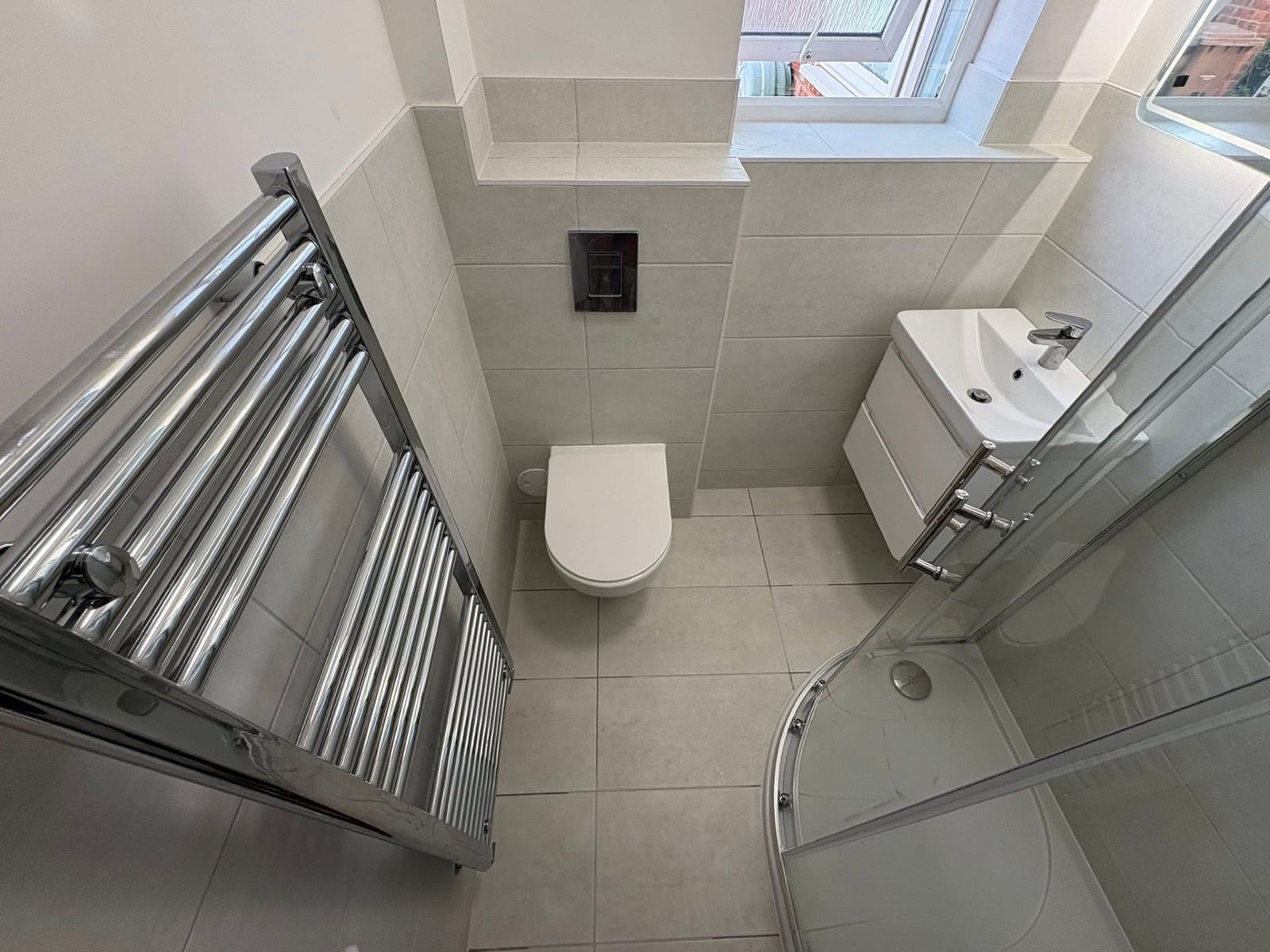 New bathroom with modern tiling, wall-hung toilet and heated towel rail