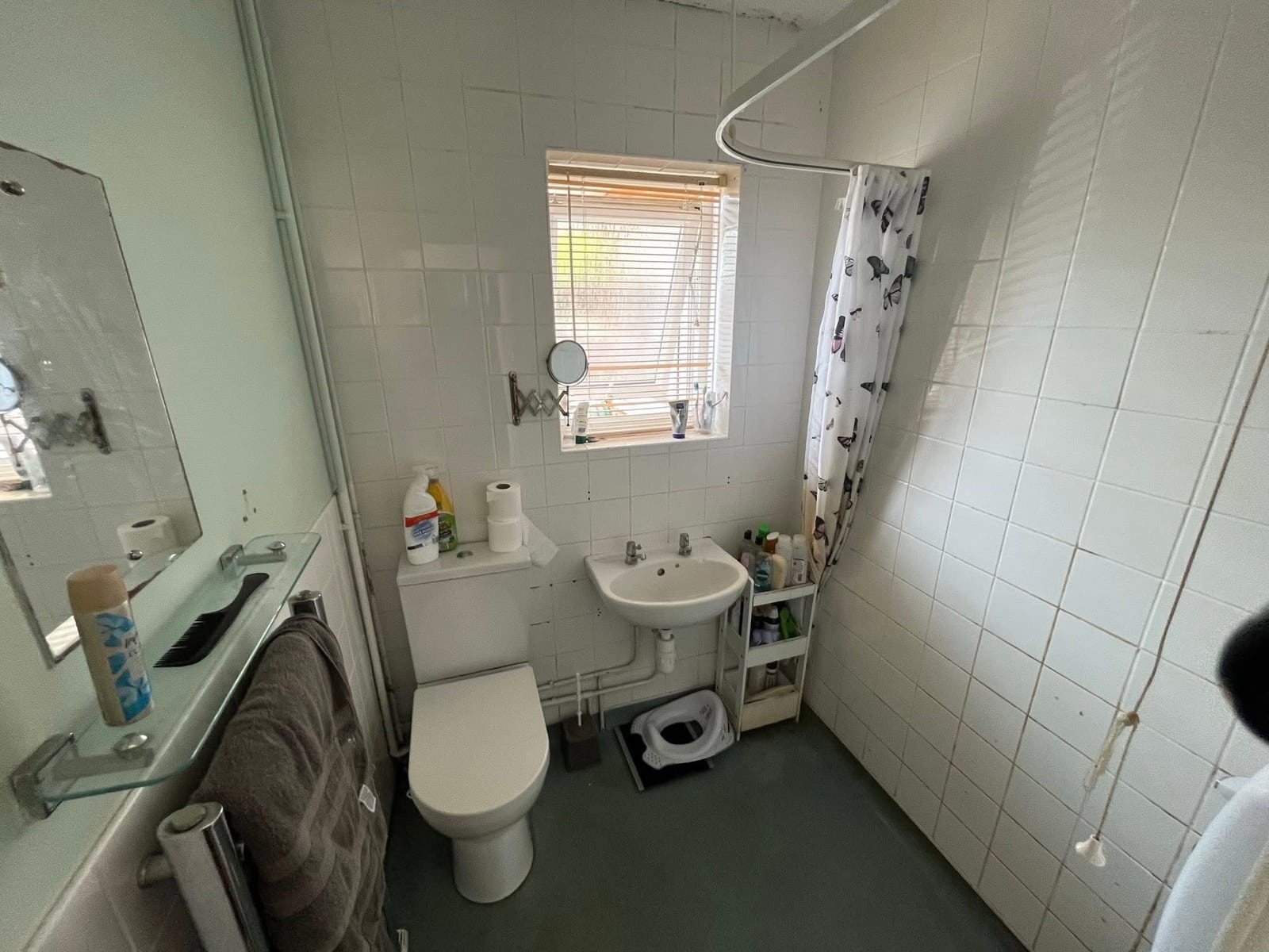 Original bathroom before works, with dated tiling, bath and shower curtain