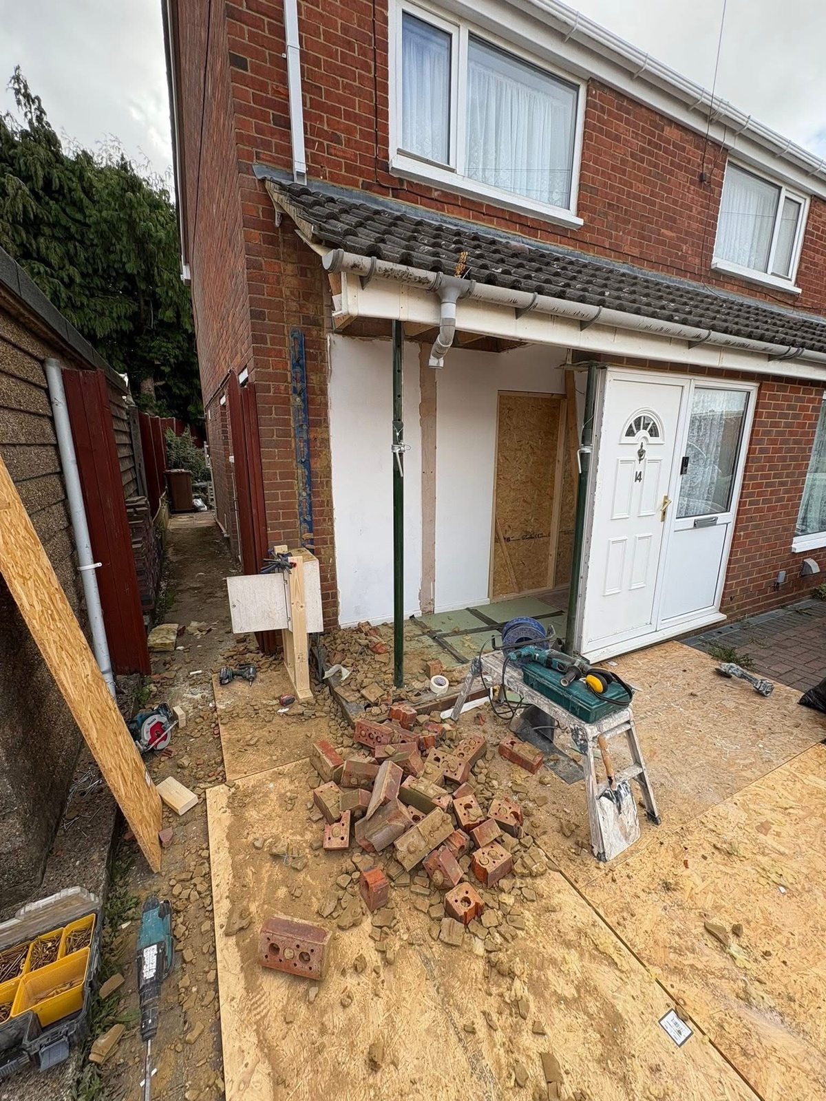 Demolition phase showing brickwork removed and acro props supporting the roof